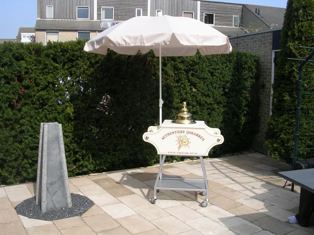 De authentieke ijskar van Vrolijk IJs met parasol op een tuinfeest